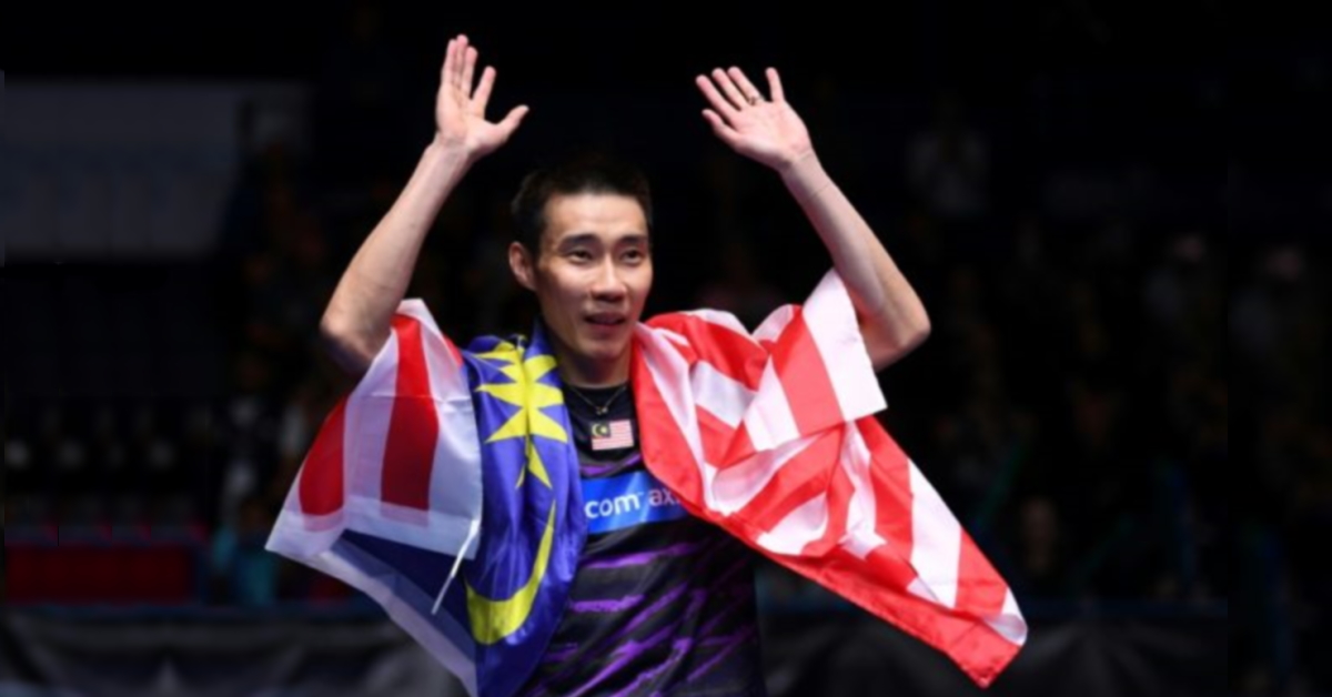 Datuk Lee Chong Wei acknowledging the crowd with arms raised and a Malaysian flag draped over his shoulders.